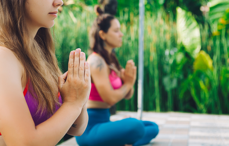 胸で手を合わせ合掌してあぐらを組む2人の女性02shutterstock ヨガジェネレーション Yogageneration