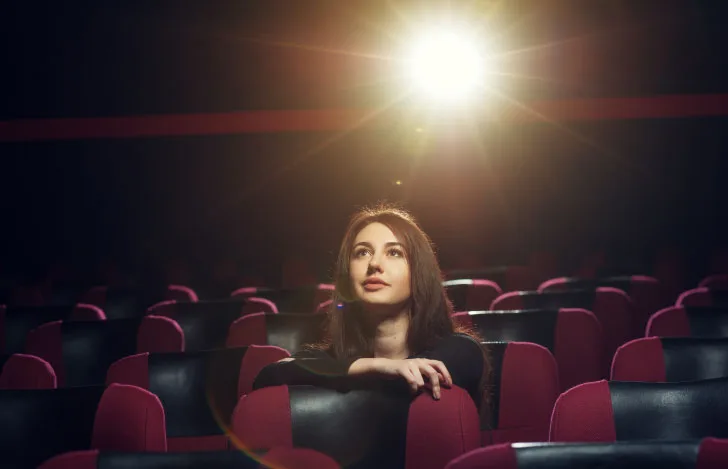 映画館でスクリーンを見上げる女性