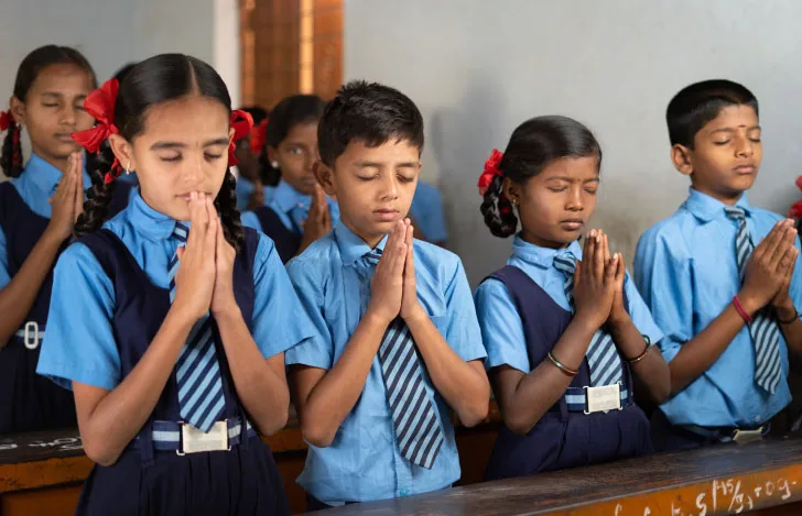 手を合わせて目を閉じるインドの学校の子どもたち